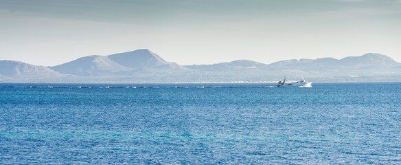 Navigating the Azure: Trawler at Sea with Mountain Backdrop