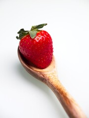 Strawberry on a wooden spoon.