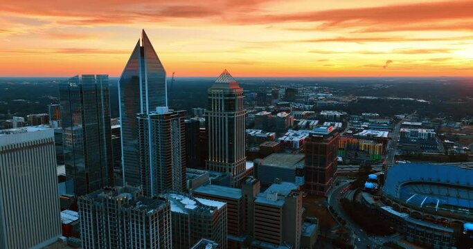 Approaching the group of beautiful skyscrapers in the uptown of Charlotte, NC, USA. Splendid orange sky over the scenery of a city. Top view.