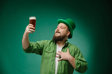 Bearded emotional man with beer on a dark green background. St. Patrick's Day banner