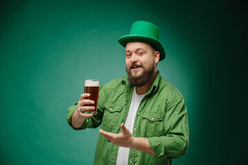 Bearded emotional man with beer on a dark green background. St. Patrick's Day banner