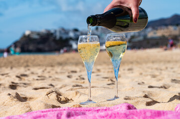 Pouring a glass of champagne on vacation, south of Fuerteventura, Canary islands, blue ocean,...