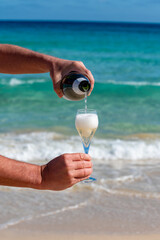 Pouring a glass of champagne on vacation, south of Fuerteventura, Canary islands, blue ocean, mountains