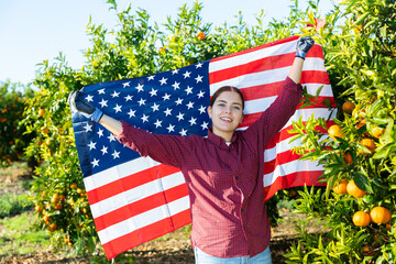 Smiling girl football fan waving United States of America flag during tangerines harvest