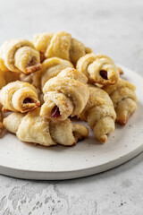 Homemade bagel cookies with dried fruits and walnuts on white plate on gray table. Sweet croissant cookies