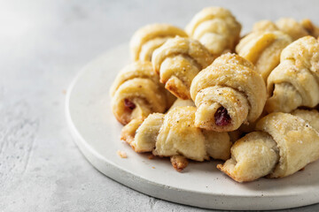 Homemade bagel cookies with dried fruits and walnuts on white plate on gray table close up. Sweet croissant cookies