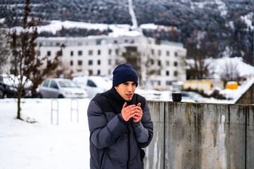 young man wrapped up in winter breathing halo of cold.drinking coffee