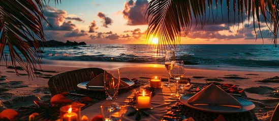 Fotobehang Romantic dinner on the beach with sunset candles with palm leaves and sunset sky and sea Amazing view honeymoon or anniversary dinner landscape Exotic island evening horizon romance for a coupl © Ilgun