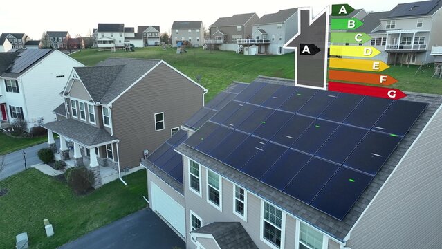 Suburban home with rooftop solar panels and 3D graphic energy efficiency rating scale. Aerial view of A rated home. Modern neighborhood using renewable and sustainable clean energy