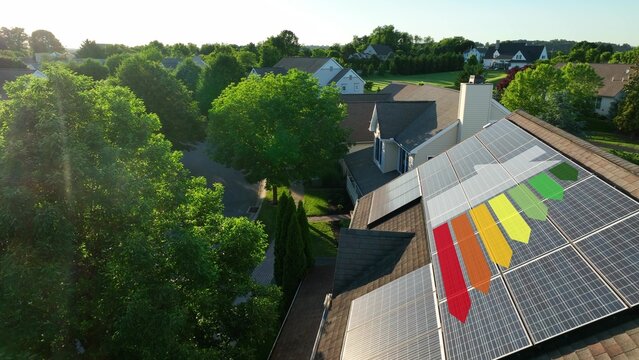 Rooftop solar panels with graphic of energy efficiency scale in a suburban neighborhood at sunset. Green energy in USA housing. 3D render, aerial