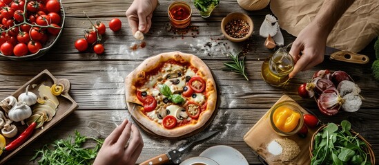 top view of boy making pizza with pizza ingredients tomatoes salami and mushrooms on wooden tabletop. Copy space image. Place for adding text