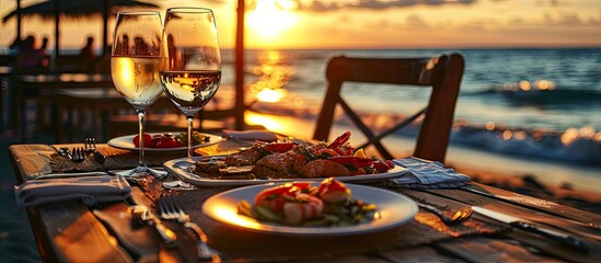 Romantic dinner at the beach restaurant overlooking the sunset on the ocean on a beautifully served table seafood and white wine. Copy space image. Place for adding text