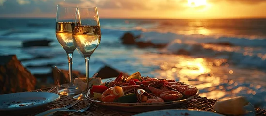 Poster Romantic dinner at the beach restaurant overlooking the sunset on the ocean on a beautifully served table seafood and white wine. Copy space image. Place for adding text © Ilgun