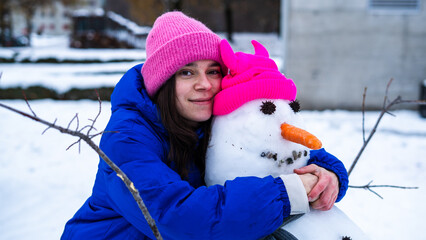 Close up Portrait of young woman hugging snowman