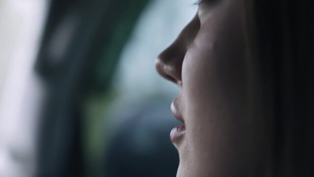 A girl is riding in a car in the passenger seat and talking. The camera takes a close-up of her face from the side