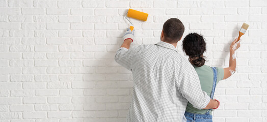 Young couple painting white brick wall. Banner for design