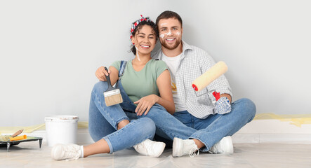 Happy young couple during painting of wall at home