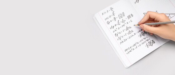 Woman writing maths formulas in copybook with pencil on grey background with space for text