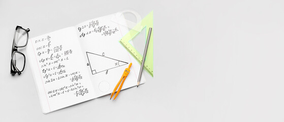 Copybook with maths formulas, glasses and stationery on grey background with space for text