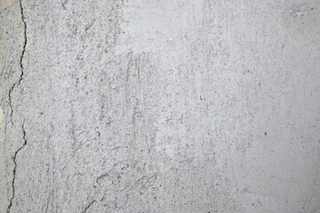 Cracks on the gray wall. Cement background. The concept of unfinished repairs.