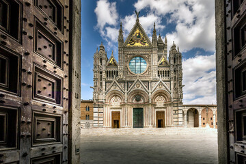Siena, Italy - July 26, 2023: Siena Cathedral is a famous Italian Romanesque and Gothic cathedral with a striking facade is crowded with sculptures and boasts three large doors - obrazy, fototapety, plakaty