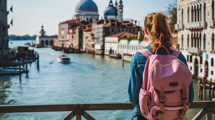 Fototapeta na wymiar Young woman traveling in Venice, Italy. Back view of female tourist with backpack looking at Grand Canal and Basilica di Santa Maria della Salute.