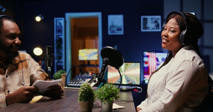 African american cohosts streaming podcast using vlogging camera during live political debate on vlog channel. Man and woman meeting in dimly lit studio to film internet show for fans - Powered by Adobe