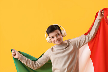 Little boy with flag of Italy listening to music on yellow background