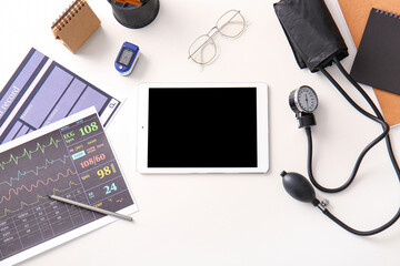 Tablet computer with medical supplies on white desk, top view