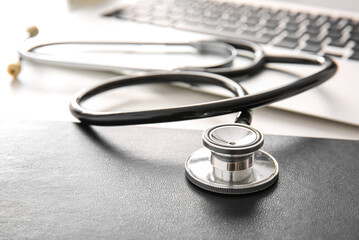 Notebook with stethoscope on white medical desk, closeup