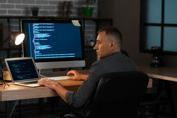 Mature male programmer working in office at night