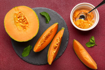 Slate board with tasty ripe melon on red background