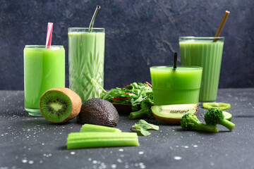 Glasses of tasty juice with fresh vegetables and fruits on black background