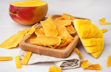 Wooden board with slices of dried mango on white background