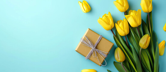 Vibrant yellow tulips with a gift box on a soft blue background.