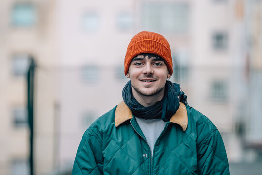 portrait of young man on the street in winter warm and wearing a hat
