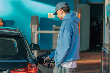 young man filling car gas tank at service station