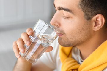 Young man drinking fresh water in kitchen