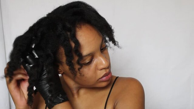 Black woman untwisting her natural 4c hair on a white background
