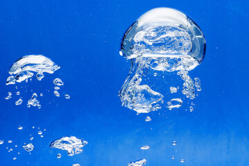 a large air bubble rises upwards in the blue water, close-up