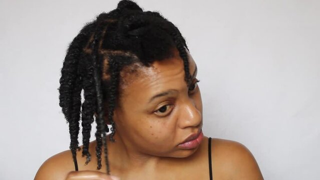 Black woman twisting her natural 4c hair on a white background
