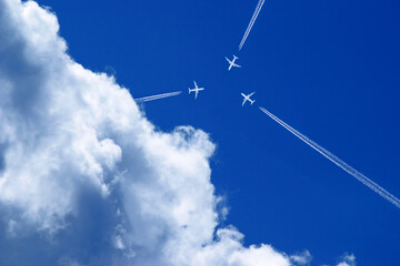 three aeroplanes with vapour trails in the blue sky fly exactly towards each other