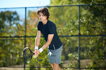 A young man hits a tennis ball on a tennis court