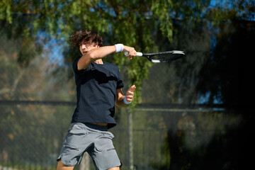 A young man hits a tennis ball on a tennis court