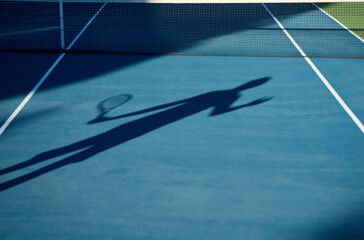 A man with long hair plays tennis on a court surrounded by trees