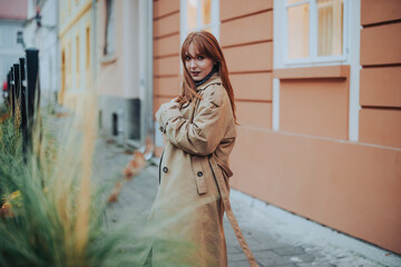 A ginger woman in a coat is seducing with her look while standing outside.