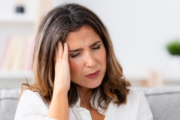 Close-up portrait of a mature woman gesturing headache at home alone - obrazy, fototapety, plakaty