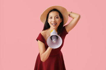 Young Asian woman with megaphone on pink background