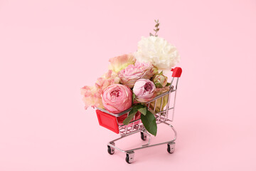 Small shopping cart with beautiful flowers on pink background © Pixel-Shot