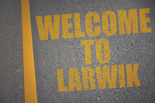 asphalt road with text welcome to Larvik near yellow line.